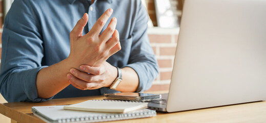 man holds painful wrist at keyboard